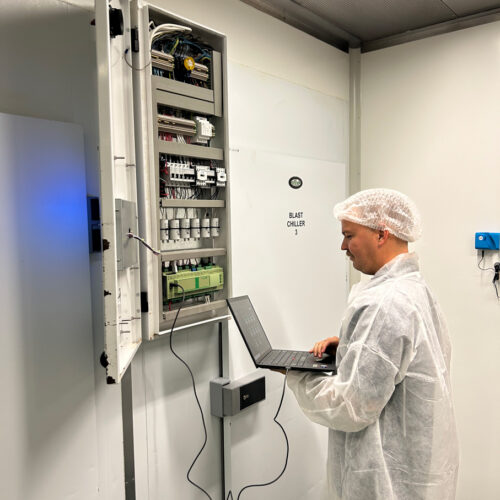 A man in a white coat operates a laptop, managing an HVAC control system at Fiona Stanley Hospital’s Main Kitchen