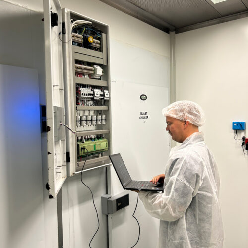 A man in a white coat operates a laptop, managing an HVAC control system at Fiona Stanley Hospital’s Main Kitchen