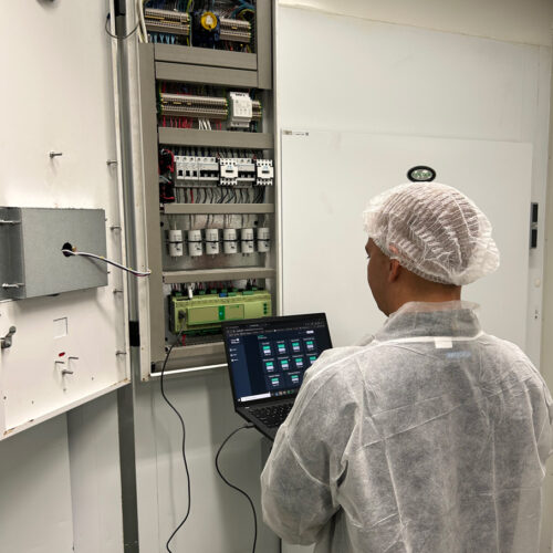 A man in a white coat operates a laptop, managing an HVAC control system at Fiona Stanley Hospital’s Main Kitchen