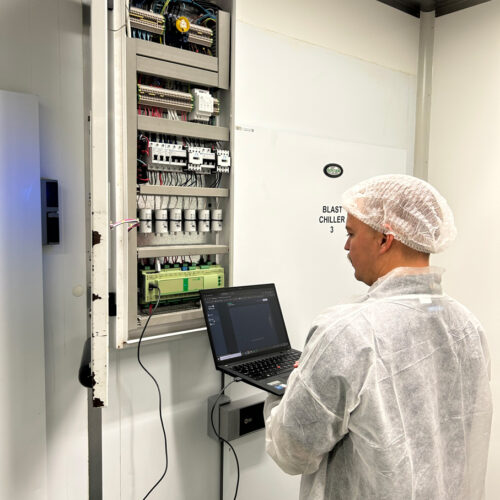 A man in a white coat operates a laptop, managing an HVAC control system at Fiona Stanley Hospital’s Main Kitchen