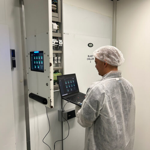 A man in a white coat operates a laptop, managing an HVAC control system at Fiona Stanley Hospital’s Main Kitchen