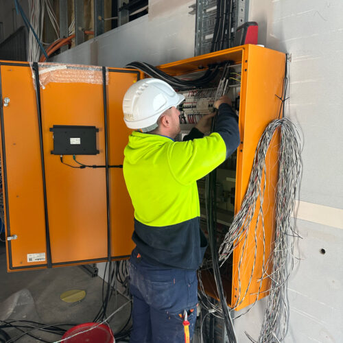 Technician in green vest and hard hat from an industrial electrical company in Perth installing switchboard at Ocean Reef Marina
