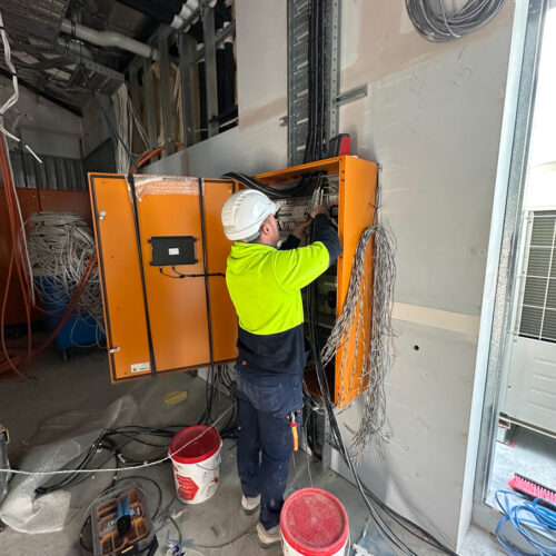 Technician in green vest and hard hat from an industrial electrical company in Perth installing switchboard at Ocean Reef Marina