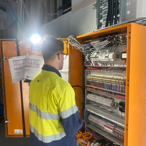 A technician in a green vest from an industrial electrical company in Perth installing a mechanical switchboard at Ocean Reef Marina site