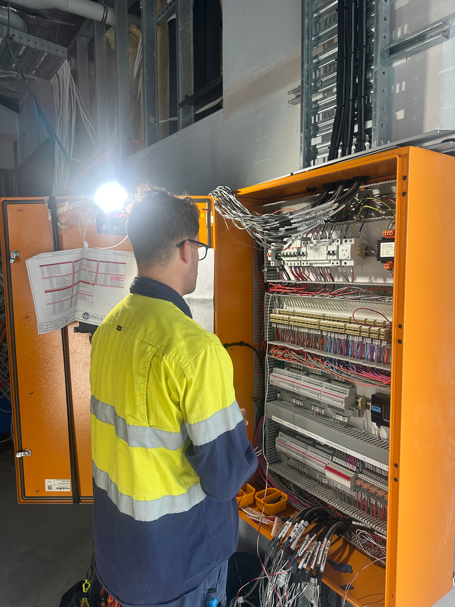 A technician in a green vest from an industrial electrical company in Perth installing a mechanical switchboard at Ocean Reef Marina site