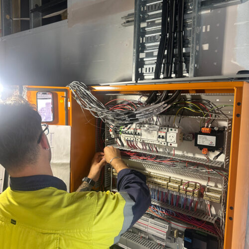 A technician in a green vest from an industrial electrical company in Perth installing a mechanical switchboard at Ocean Reef Marina site