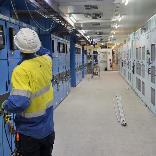 A technician adjusts settings on a large electrical panel for an HVAC control system in a mechanical room