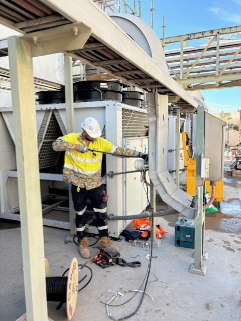 An electrical mechanic adjusts settings on a large industrial HVAC control system, ensuring optimal performance and efficiency