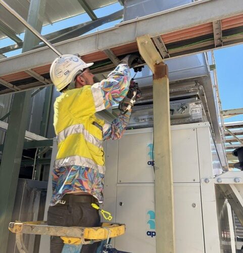 Worker adjusting HVAC control system at Boddington Gold Mine building ensuring optimal climate control and system performance for operations