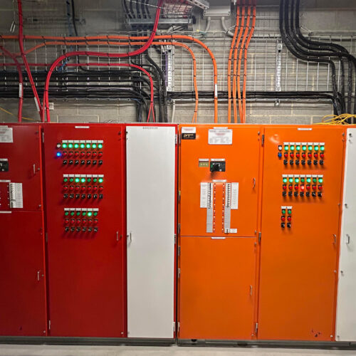 A room with multiple electrical control panels and wiring installed by MECS for industrial electrical control panel systems setup