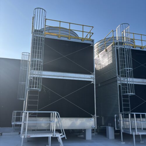 Two prominent industrial heat exchangers positioned on a building's roof, integral to the mechanical services switchboards system installation