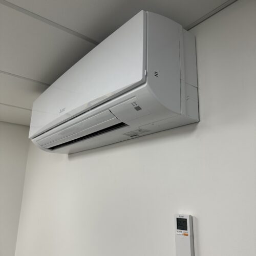 Wall-mounted white air conditioner with remote control, part of HVAC control system installation and building climate management setup